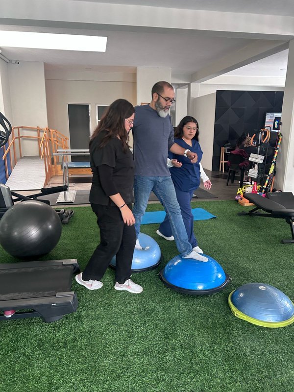 Fisioterapeuta apoya a paciente en ejercicio de equilibrio sobre bosu en Lumive Fisioterapia